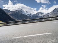 a bike is on a mountain highway with snow covered mountains in the background and the road has no traffic