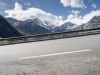 a bike is on a mountain highway with snow covered mountains in the background and the road has no traffic