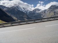 a bike is on a mountain highway with snow covered mountains in the background and the road has no traffic