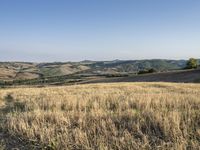 a bike is parked in the middle of a field near the hillside of a hilly country side