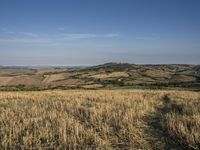 a bike is parked in the middle of a field near the hillside of a hilly country side