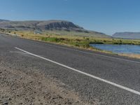 a bike parked along the side of the road with mountains in the distance and water in the background