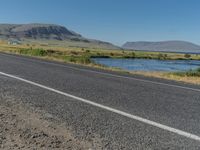 a bike parked along the side of the road with mountains in the distance and water in the background