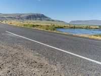 a bike parked along the side of the road with mountains in the distance and water in the background