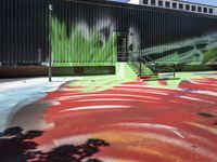 a bike on a rainbow painted road by a building with stairs in the background and a painting of green leaves