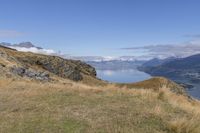 a person on a bike on a steep incline over a lake and mountains with a view