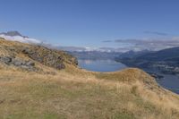 a person on a bike on a steep incline over a lake and mountains with a view