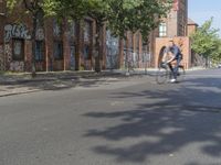 an image of a man riding his bike on the street in the city street past some buildings