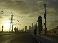 an empty highway with power lines leading to city buildings in the back ground and road tracks