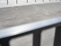 a person riding a bike on a paved area near street and a motorcycle racking area