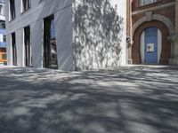 a man on a bike riding down a sidewalk near some buildings and a tree with a blue door