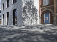 a man on a bike riding down a sidewalk near some buildings and a tree with a blue door