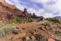 a person riding a bike through the desert in front of rocky hills and cliffs,