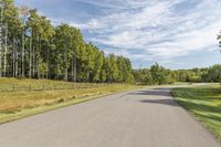 a bike is riding down the street near a wooded area with trees in the background