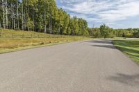 a bike is riding down the street near a wooded area with trees in the background