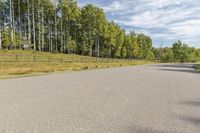 a bike is riding down the street near a wooded area with trees in the background