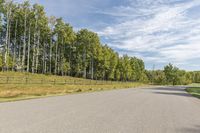 a bike is riding down the street near a wooded area with trees in the background