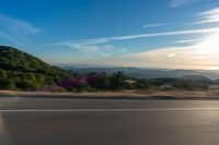 a man is riding his bike along the side of the road in front of mountains