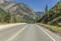 a bike sits on the side of the road near trees and rocks a mountain range