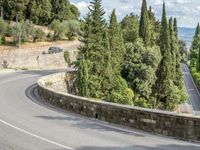 a bike and scooter riding down the side of a curvy road