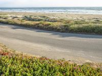 a person on a bike in the middle of the road looking out to the ocean