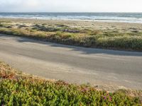 a person on a bike in the middle of the road looking out to the ocean