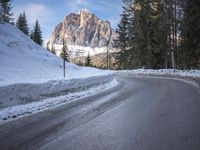 a person riding a bike on a snow covered road near a mountain peak in the background