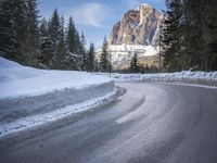 a person riding a bike on a snow covered road near a mountain peak in the background