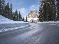 a person riding a bike on a snow covered road near a mountain peak in the background