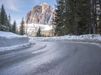 a person riding a bike on a snow covered road near a mountain peak in the background