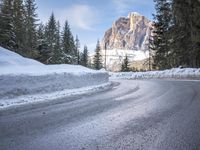 a person riding a bike on a snow covered road near a mountain peak in the background