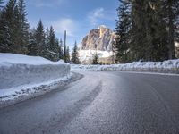 a person riding a bike on a snow covered road near a mountain peak in the background