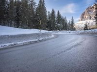 a person riding a bike on a snow covered road near a mountain peak in the background