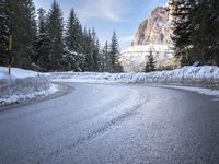 a person riding a bike on a snow covered road near a mountain peak in the background