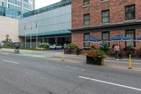 people are riding bikes down a paved street next to an office building with tall windows