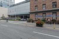 people are riding bikes down a paved street next to an office building with tall windows