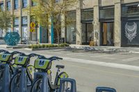 bikes parked in the middle of a street by a building with people walking along the side of the street