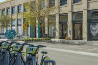 bikes parked in the middle of a street by a building with people walking along the side of the street