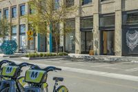 bikes parked in the middle of a street by a building with people walking along the side of the street