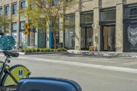 bikes parked in the middle of a street by a building with people walking along the side of the street