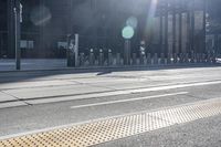 a couple of bikes are parked on a road side near a tall building, and a bike rack in the center of it