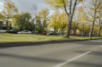 a guy riding his bike down an empty road with lots of trees behind him in a blurry photo