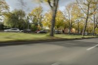 a guy riding his bike down an empty road with lots of trees behind him in a blurry photo