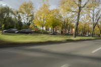 a guy riding his bike down an empty road with lots of trees behind him in a blurry photo