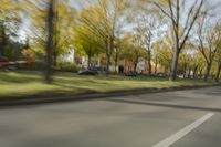 a guy riding his bike down an empty road with lots of trees behind him in a blurry photo