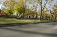 a guy riding his bike down an empty road with lots of trees behind him in a blurry photo