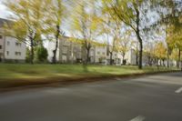 a guy riding his bike down an empty road with lots of trees behind him in a blurry photo