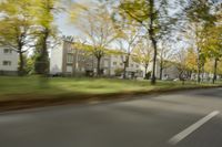 a guy riding his bike down an empty road with lots of trees behind him in a blurry photo