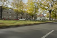 a guy riding his bike down an empty road with lots of trees behind him in a blurry photo