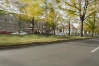 a guy riding his bike down an empty road with lots of trees behind him in a blurry photo